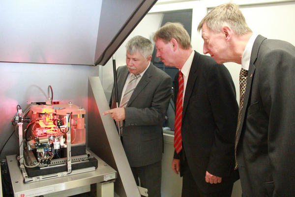Gesch&auml;ftsf&uuml;hrer Dr. Walther Schott pr&auml;sentiert seinen G&auml;sten die von der SIOS GmbH entwickelte Nanomess- und Positioniermaschine.