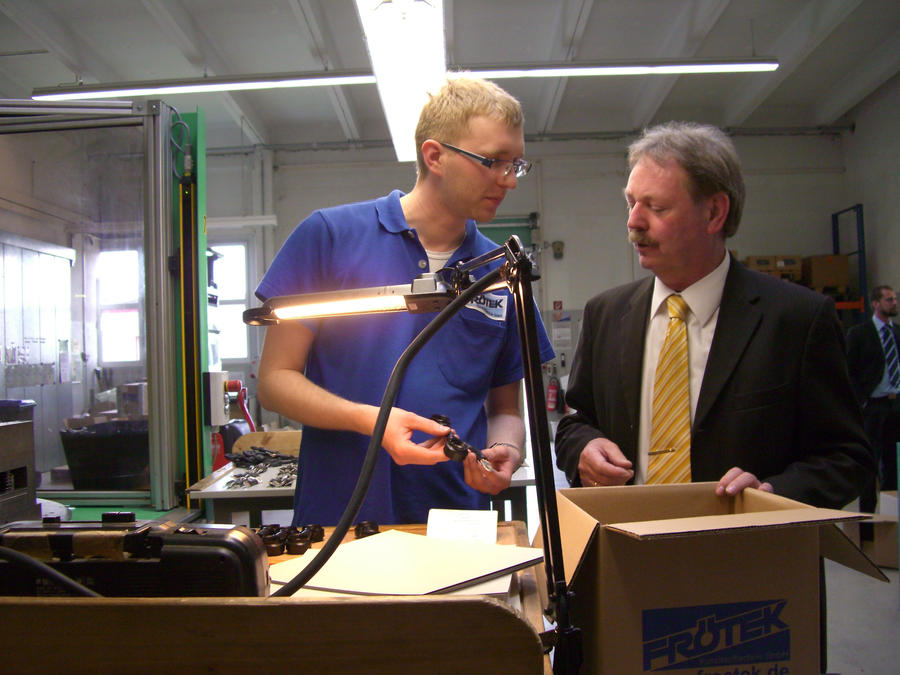 Dr. B. Kaufhold im Gespr&auml;ch mit dem Auszubildenden Stefan Raue vor der Rundtischspritzgussmaschine