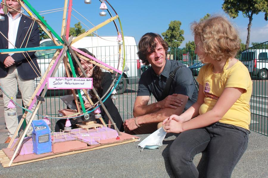 Landr&auml;tin Petra Enders und Klimaschutzmanager Felix Schmigalle im Gespr&auml;ch mit der Stadtilmer Grundsch&uuml;lerin Marie Ernst zu ihrem Solarmodell, einem Riesenrad.