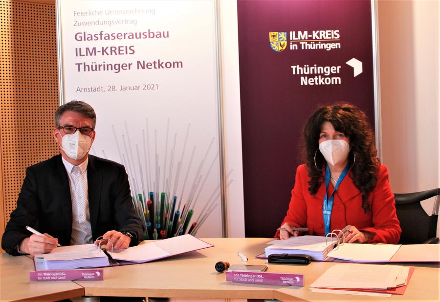 Karsten Kluge, Geschäftsführer der Thüringer Netkom, und Landrätin Petra Enders unterschreiben den Vertrag zum Glasfaserausbau im Ilm-Kreis.