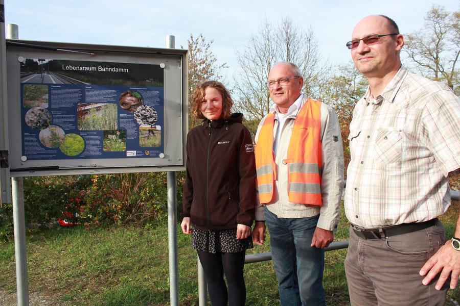 Ulrike N&uuml;ssler (Naturschutzbeh&ouml;rde), Uwe Kr&uuml;ger von der Deutschen Bahn und Andreas Mehm von der Naturschutzbeh&ouml;rde zeigen das neue Plakat, das in Stadtilm auf den Lebensraum Bahndamm hinweist.